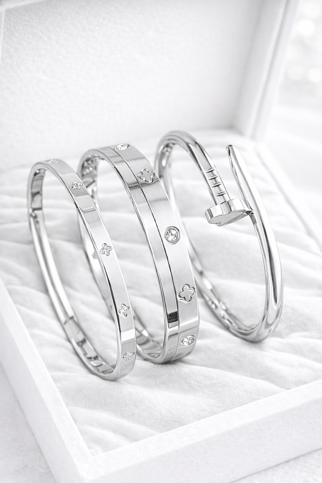 Three silver bangles with embedded stones on a white surface