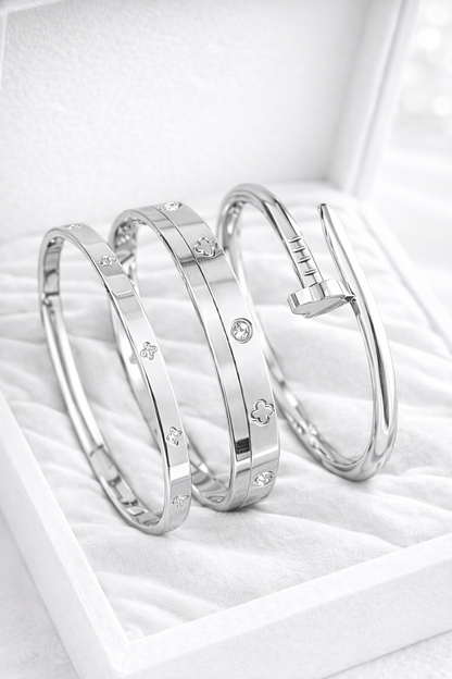 Three silver bangles with embedded stones on a white surface