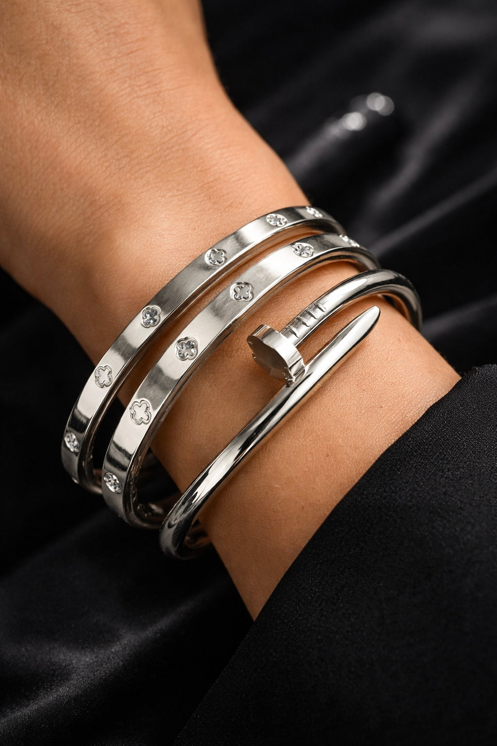 Silver bracelets with gemstones on a wrist against a black background
