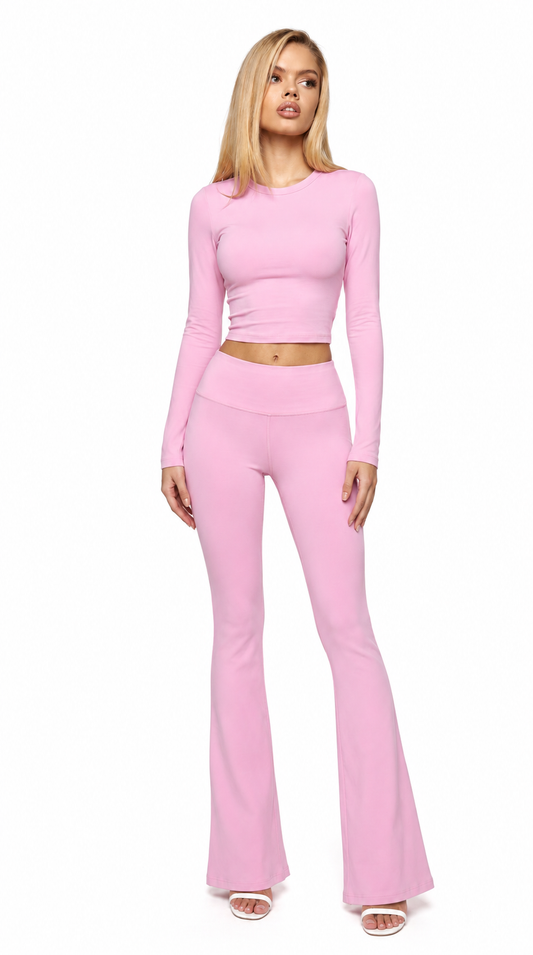 Woman wearing a pink long-sleeve top and flared pants on a white background