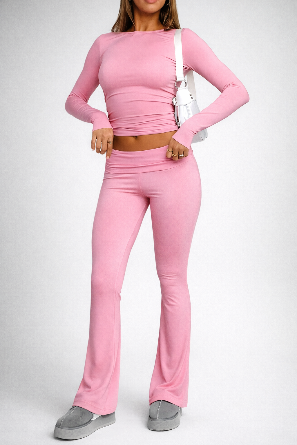 Person wearing a pink long-sleeve top and flared pants on a white background