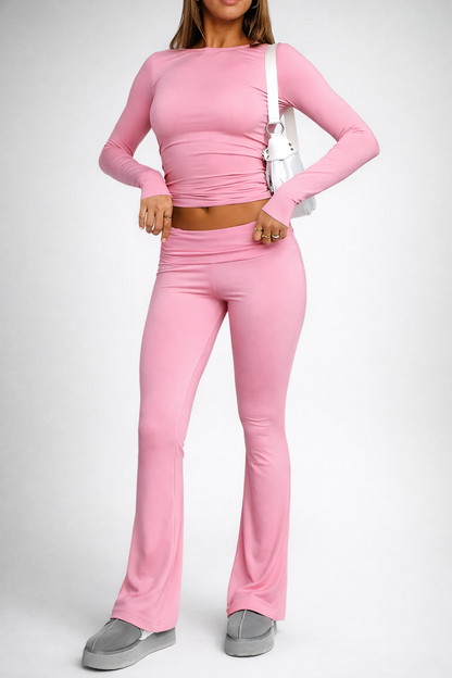 Person wearing a pink long-sleeve top and flared pants on a white background