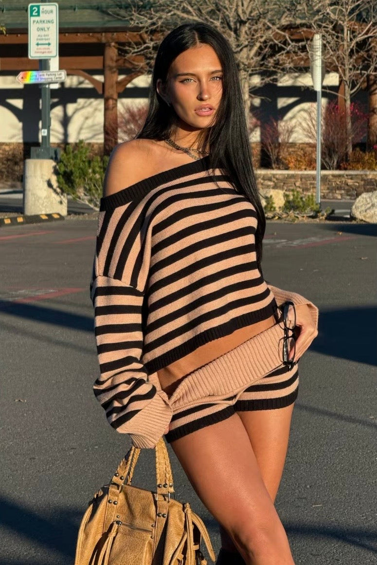 Woman wearing a black and beige striped sweater and skirt in an outdoor setting