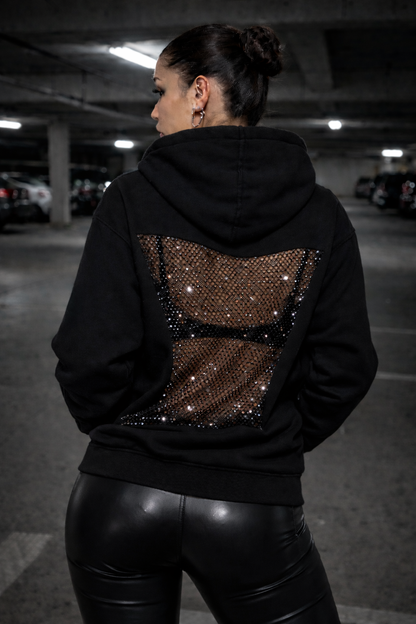 Person wearing a black hoodie with a sequin design in a parking garage